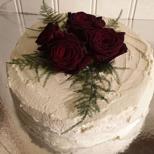 Bröllopstårta uppstruken med grädde, dekorerad med levande rosor